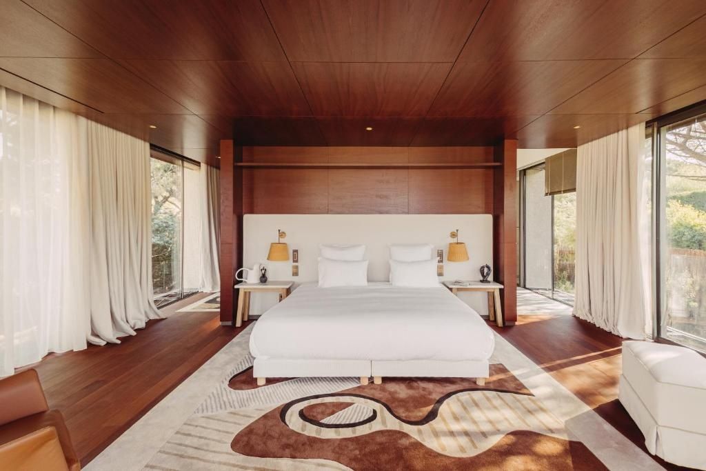 Modernes Schlafzimmer mit weißem Doppelbett, Holzdecke und großem Teppich.