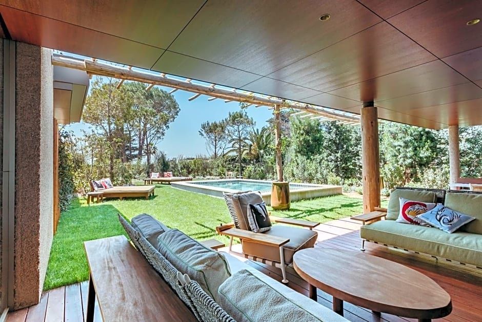 Überdachte Holzterrasse mit Sesseln, Holztisch und Blick auf den Pool im grünen Garten.