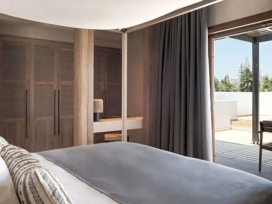 Helles Hotelzimmer mit Himmelbett, Holzschränken und Zugang zur sonnigen Terrasse.