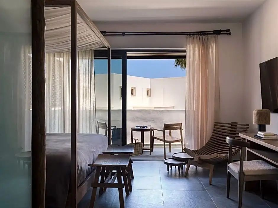 Hotelzimmer mit Himmelbett aus Holz, Sitzgelegenheiten und Zugang zur Terrasse.