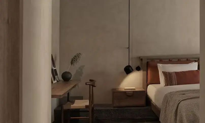 Arbeitsbereich im Hotelzimmer mit Holztisch, Stuhl und hängender Nachttischlampe.