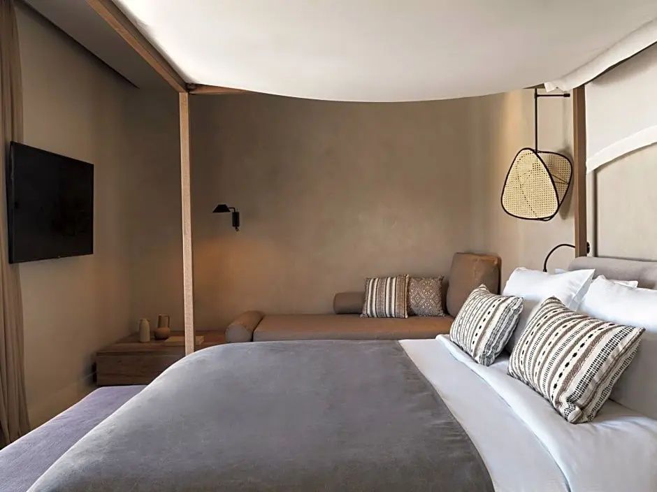 Modernes Schlafzimmer mit weißem Bett, gemütlichem Tagesbett und sanften Naturtönen.