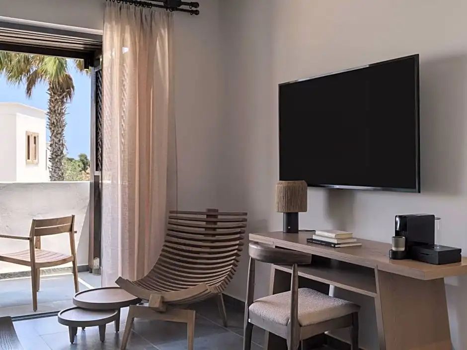 Sitzbereich im Hotelzimmer mit Holzstuhl, Schreibtisch und Wandfernseher.