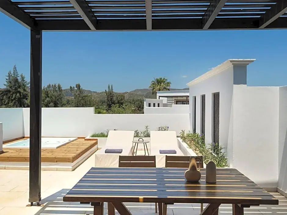 Sonnige Dachterrasse mit Esstisch, zwei Sonnenliegen und Whirlpool im Außenbereich.