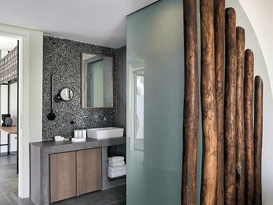 Badezimmer mit Waschbecken, Spiegel an einer Kieselsteinwand und Holzdekor.