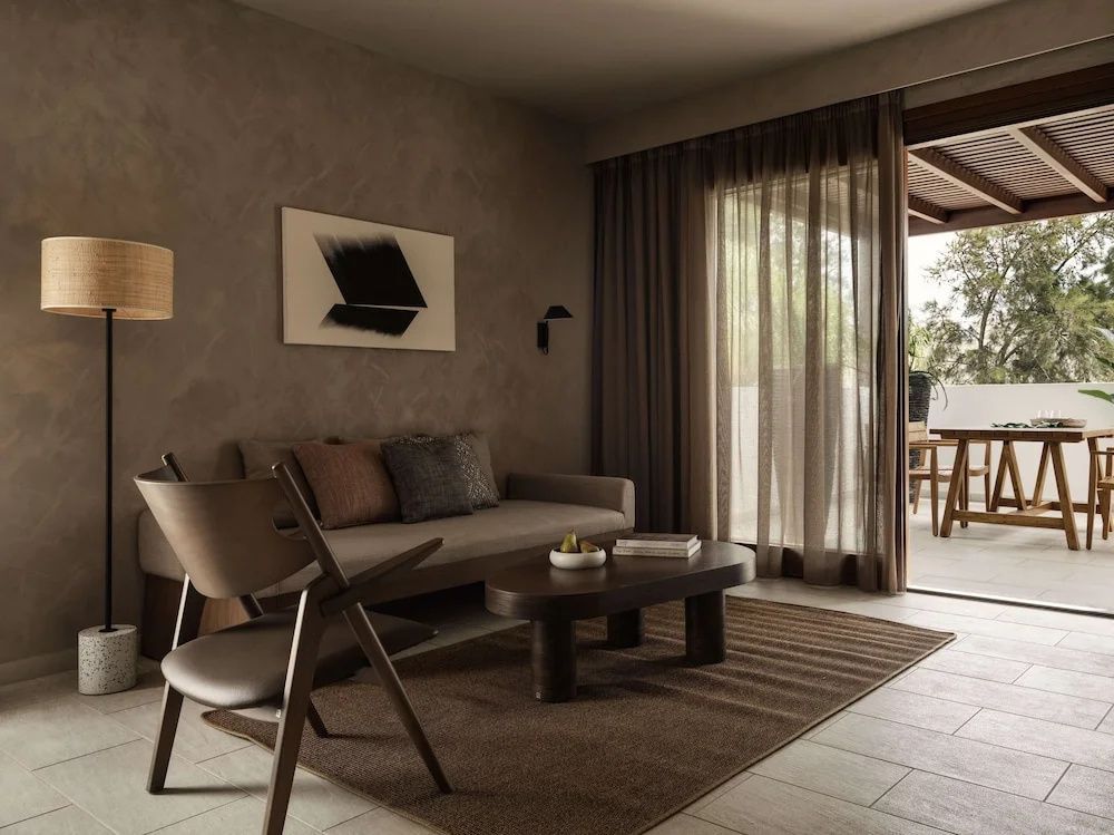 Sitzbereich in einer Suite mit Couch, hölzernem Couchtisch, Sessel und Blick auf die Terrasse.