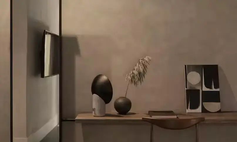 Dekoration auf einem Holzschreibtisch mit Vase, Trockenblume und einer schwarzen Tischleuchte.