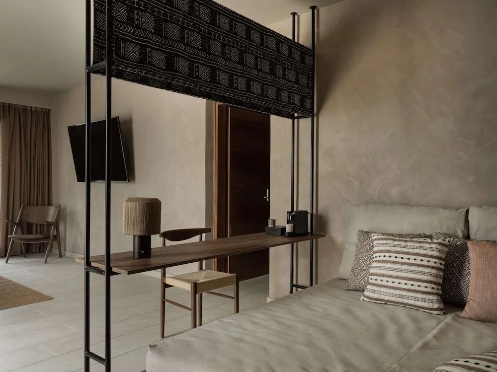 Modernes Hotelzimmer mit Bett, Raumteiler inklusive Schreibtisch und Stuhl.