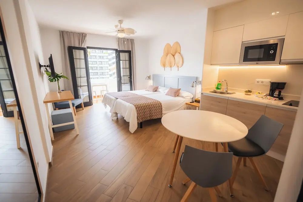 Helles Studio mit Doppelbett, Küchenzeile, Esstisch und Zugang zum Balkon.