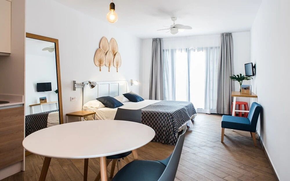 Heller Schlafbereich im Apartment mit Doppelbett, Esstisch und großen Balkonfenstern.