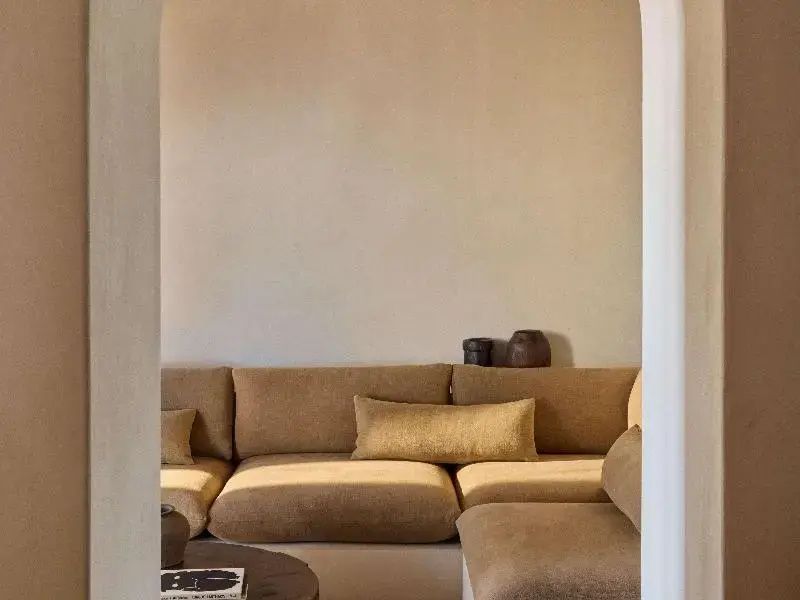 Sitzbereich mit einem beigefarbenen Polstersofa vor einer hellen Wand.