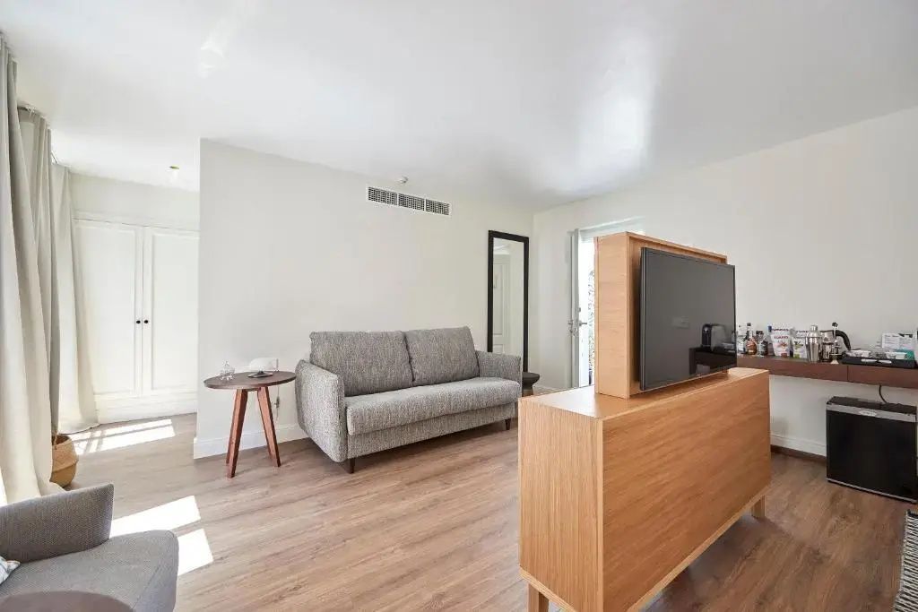Sitzbereich mit grauem Sofa, Holz-Sideboard samt Fernseher und einem Beistelltisch.