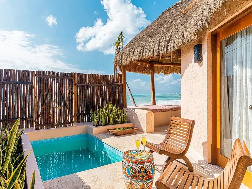 Private Terrasse mit kleinem Pool, Holzstühlen und Blick auf den Strand und das Meer.