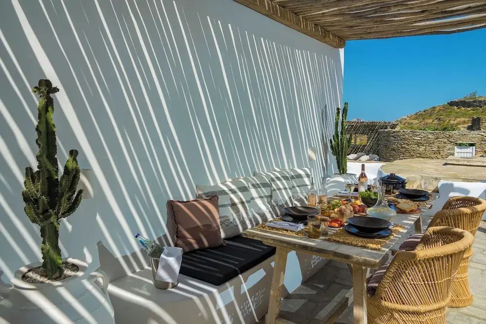 Schattige Terrasse mit gemauerter Sitzbank, Holztisch und Blick ins Freie.