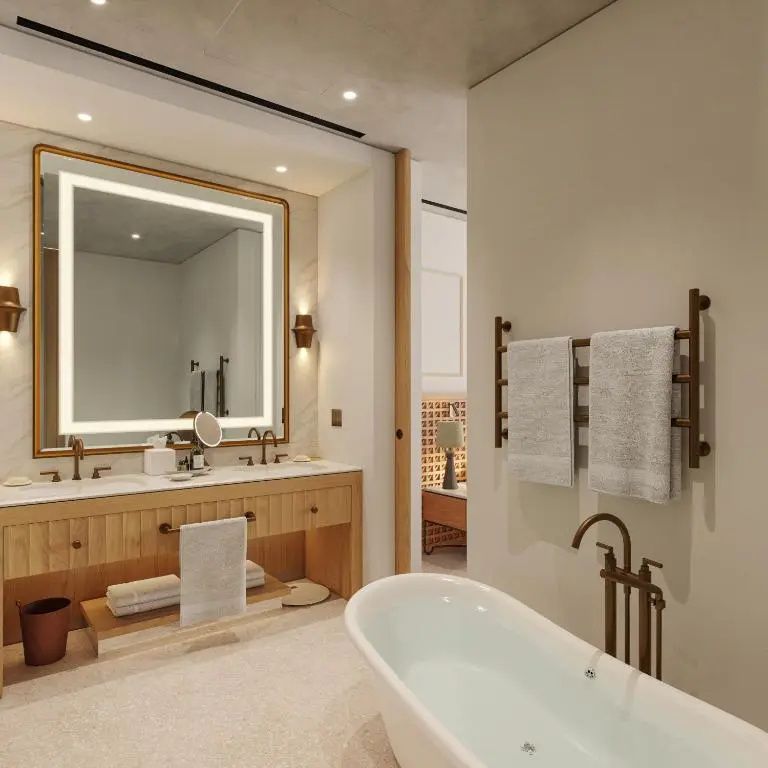 Modernes Badezimmer mit freistehender Badewanne, Doppelwaschtisch und beleuchtetem Spiegel.