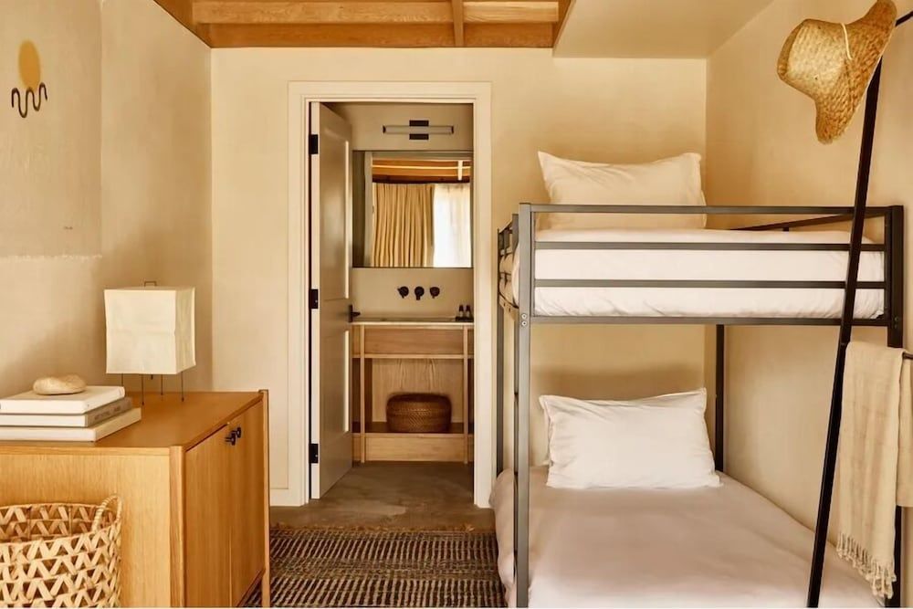 Schlafbereich mit Etagenbett aus Holz und Blick ins angrenzende Badezimmer.