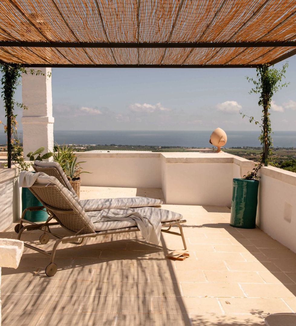 Sonnenterrasse mit Sonnenliegen, Überdachung und Blick auf das Meer.