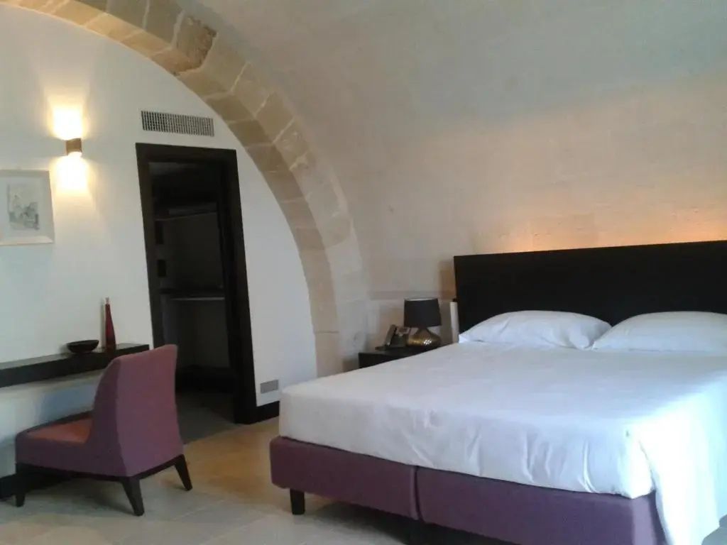 Schlafzimmer mit einem Doppelbett unter einem Gewölbe aus hellem Naturstein.