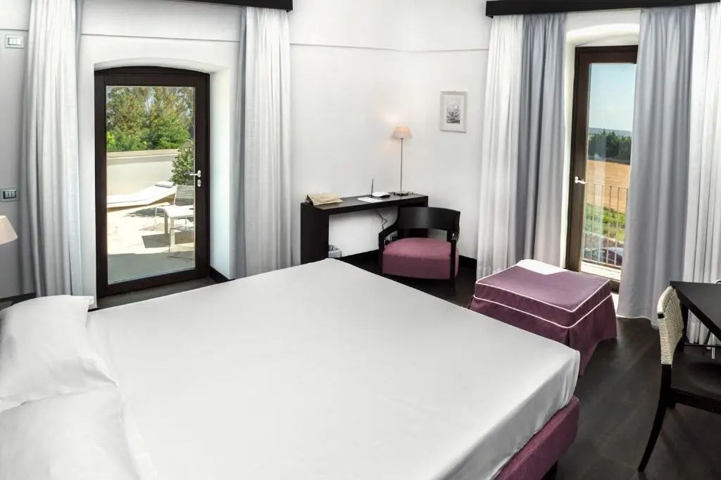 Geräumiges Schlafzimmer mit Doppelbett, Sitzgelegenheiten und Zugang zur Terrasse.