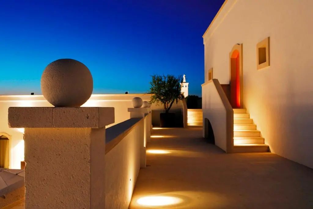 Beleuchtete Dachterrasse einer traditionellen Masseria bei Abenddämmerung.