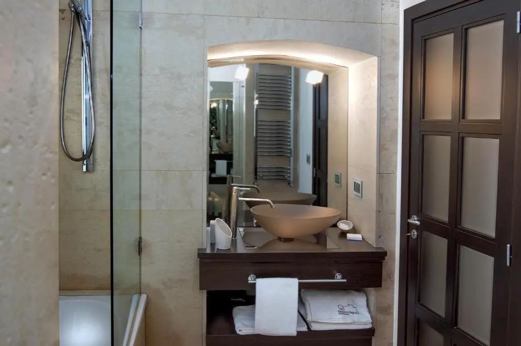 Badezimmer mit modernem Aufsatzwaschbecken, Spiegel in einer Steinnische und Handtüchern.