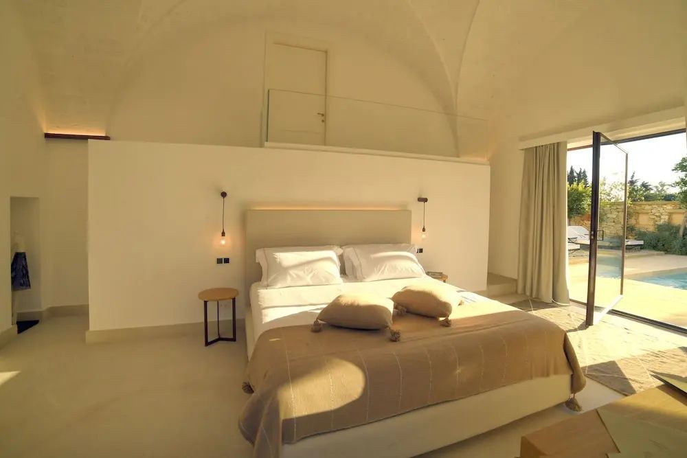 Schlafzimmer mit Doppelbett unter weißer Gewölbedecke und seitlichem Tageslichteinfall.