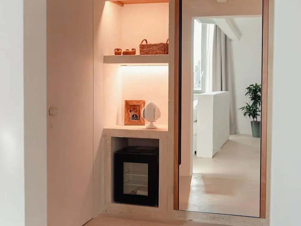 Wandeinbau mit Beleuchtung, Minibar, kleiner Dekoration und anliegendem Spiegel im Zimmer.