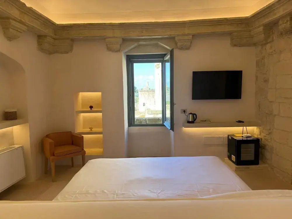 Doppelbett in einem Hotelzimmer mit Fenster nach draußen und Fernseher an der Wand.