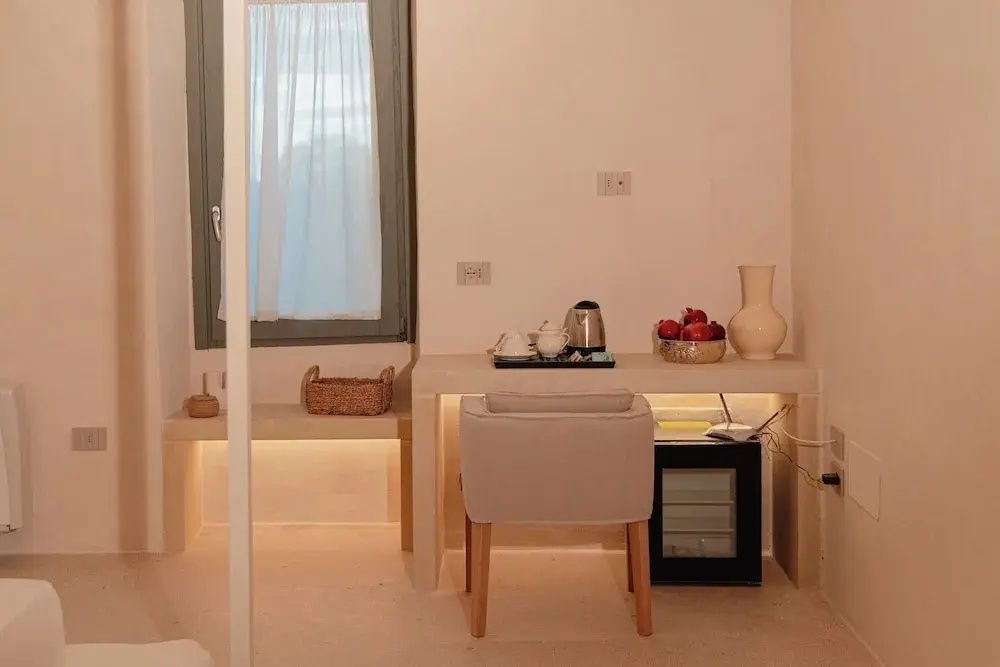 Schreibtisch im Zimmer mit Minibar, Wasserkocher, Teeset und einer Schale Obst.