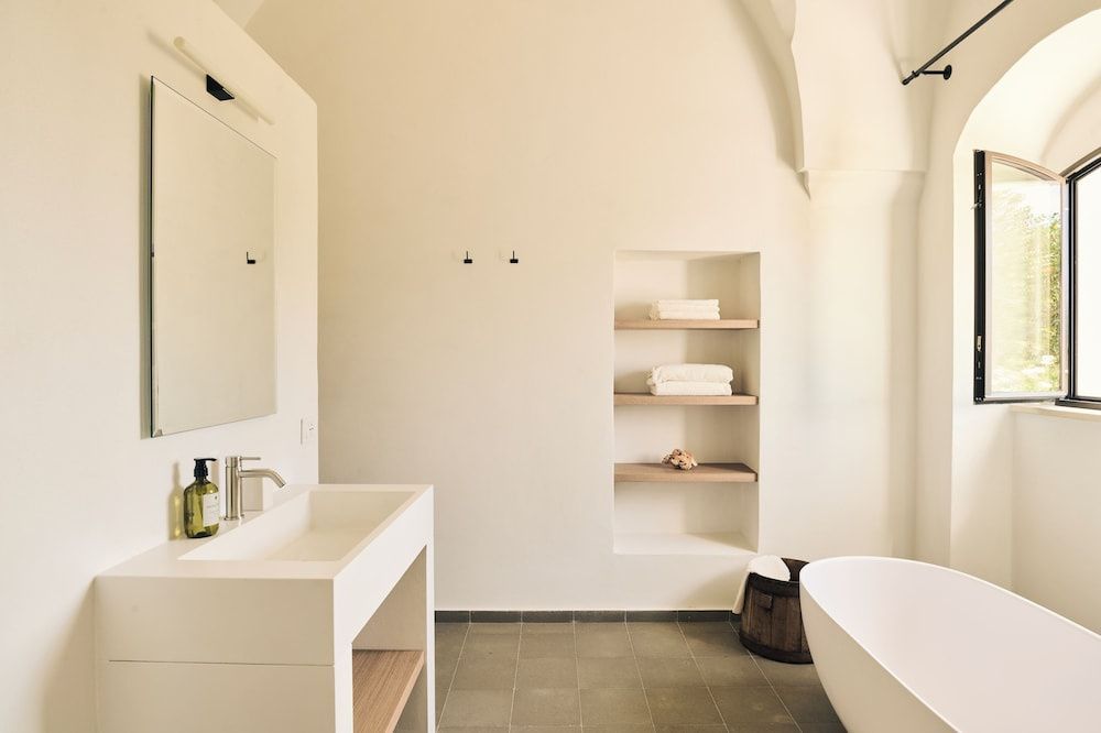 Badezimmer mit modernem Waschtisch, integrierter Wandnische für Handtücher und Badewanne.