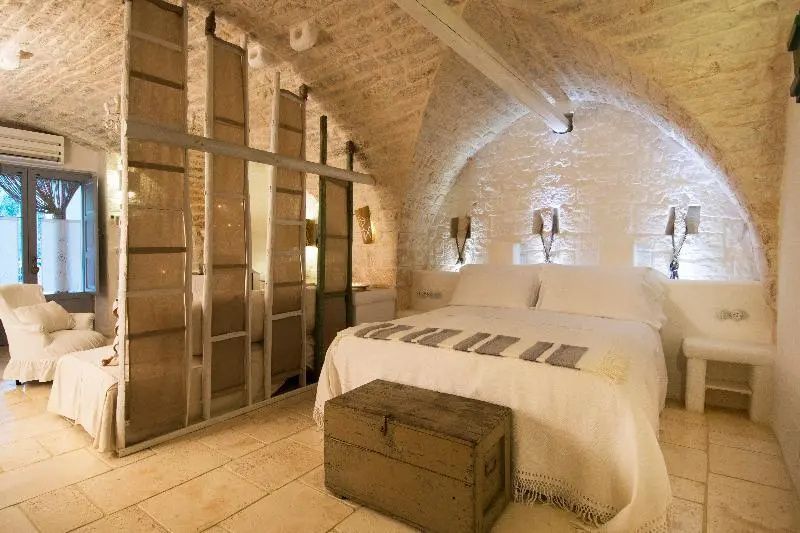 Schlafzimmer in einem historischen Steingewölbe mit Doppelbett und Holztruhe.