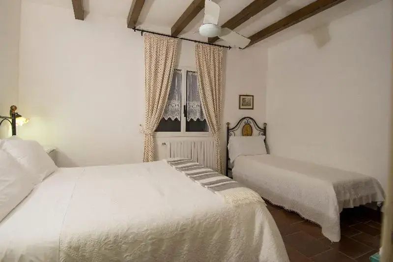 Schlafzimmer mit Holzbalkendecke, einem großen Doppelbett und einem Einzelbett.