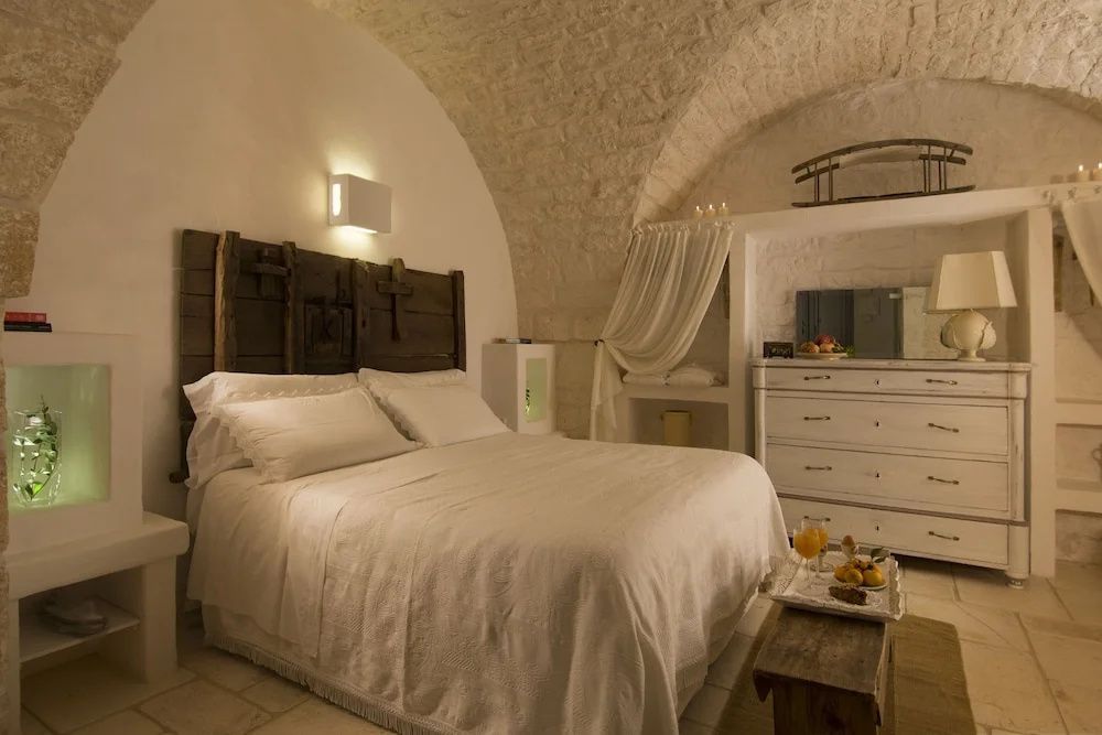 Hotelzimmer unter einem Steingewölbe mit Doppelbett und weißer Kommode.