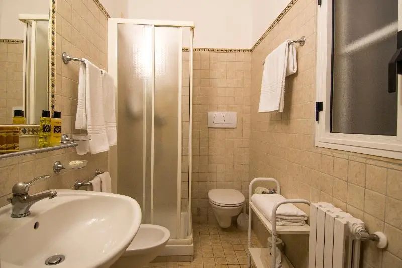 Badezimmer mit Dusche, Toilette, Waschtisch und hellen Wandfliesen.