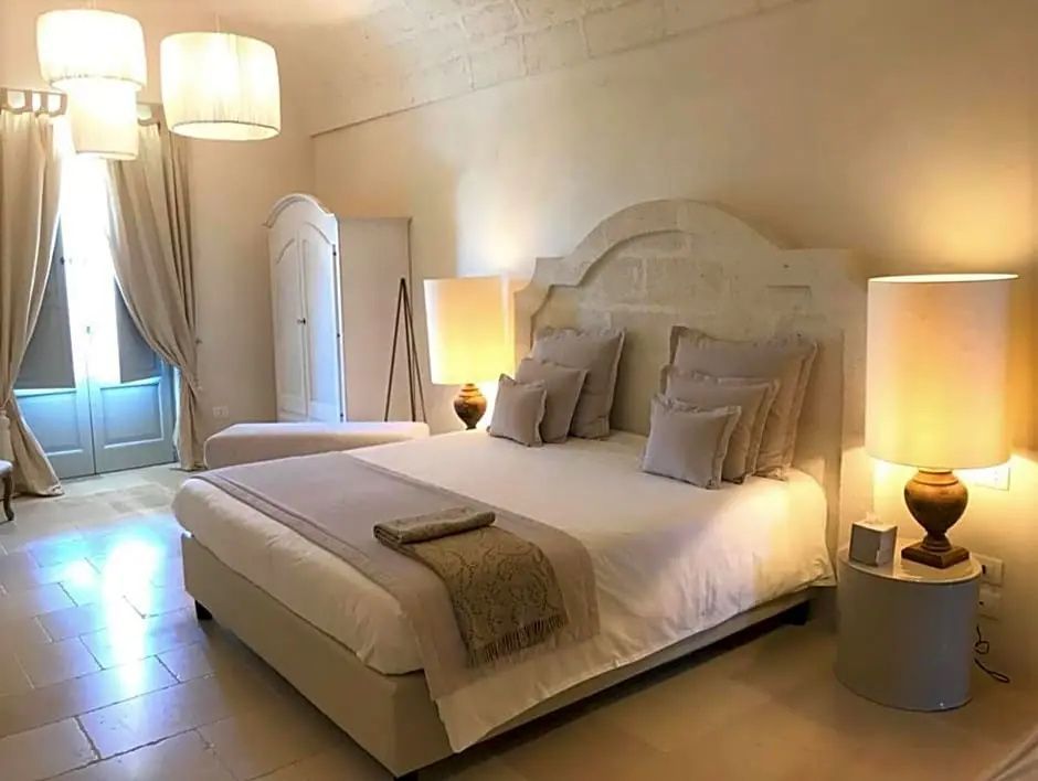 Helles Hotelzimmer mit großem Doppelbett, beigen Kissen und hellen Möbeln.