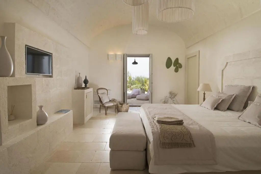 Helles Schlafzimmer mit Steingewölbe, Doppelbett und geöffneter Tür zur Terrasse.