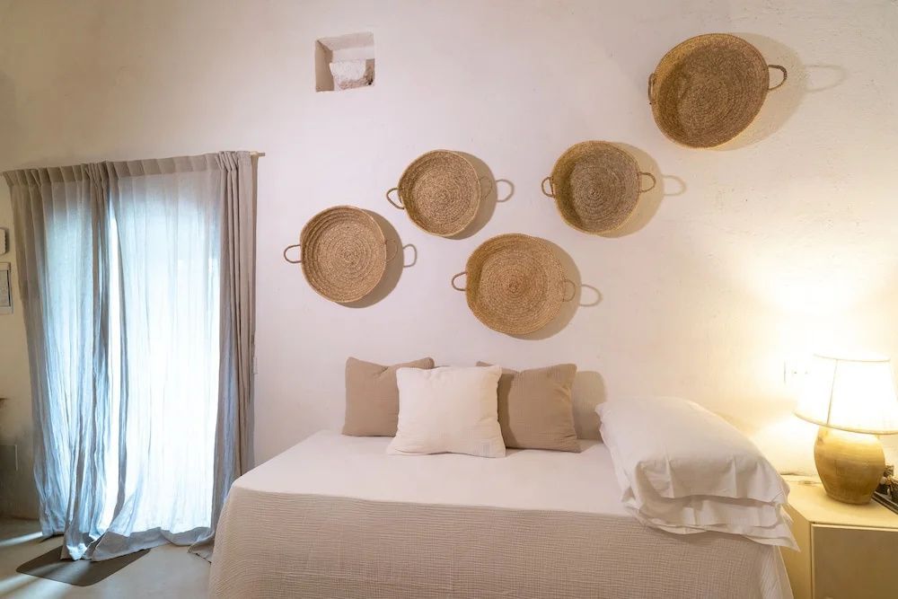 Bett mit hellen Kissen und geflochtenen Körben als Dekoration an der Wand.