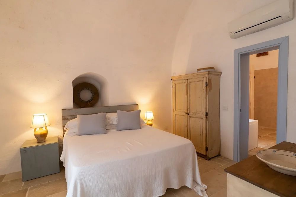 Schlafzimmer mit Doppelbett, hellem Tonnengewölbe und Holzschrank.