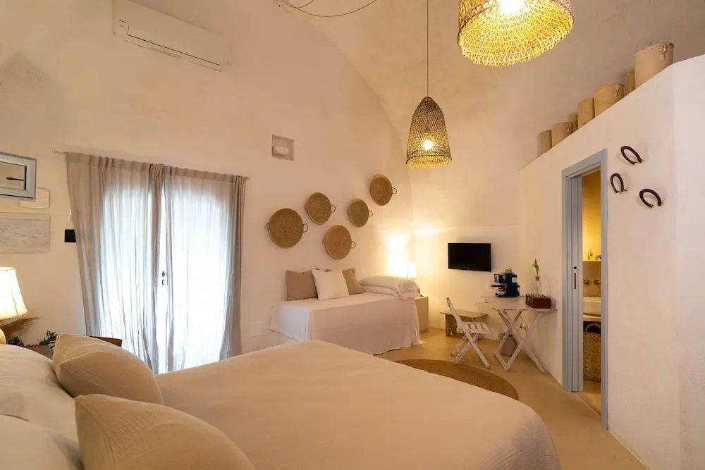 Geräumiges Hotelzimmer mit hellen Wänden, Gewölbedecke, Bett und Tagesbett.