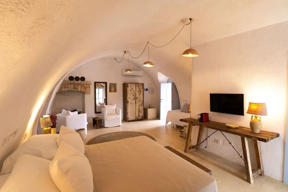 Helles Hotelzimmer mit Doppelbett, Sesseln und rustikalem Schrank.