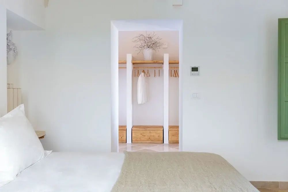 Blick in einen begehbaren Kleiderschrankbereich mit Holzregalen und aufgehängten Bademänteln.