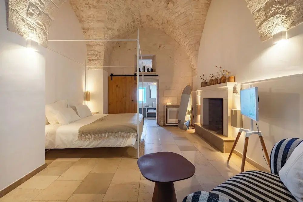 Geräumiges Zimmer mit einem Himmelbett, Steingewölbe und Kamin an der Steinwand.