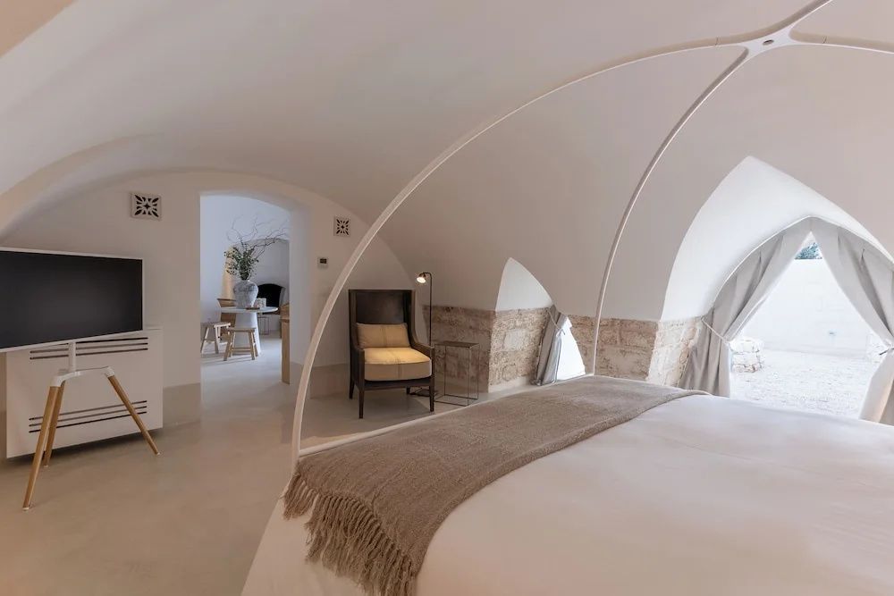 Perspektive auf das Baldachinbett, einen Sessel und den Durchgang zum Nebenraum.