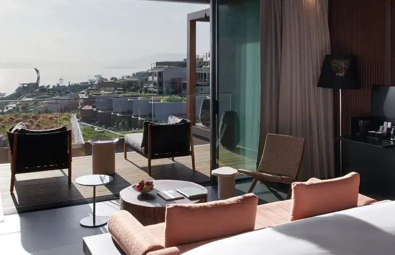 Blick aus dem Hotelzimmer über eine Terrasse auf das Meer und die umliegenden Gebäude.
