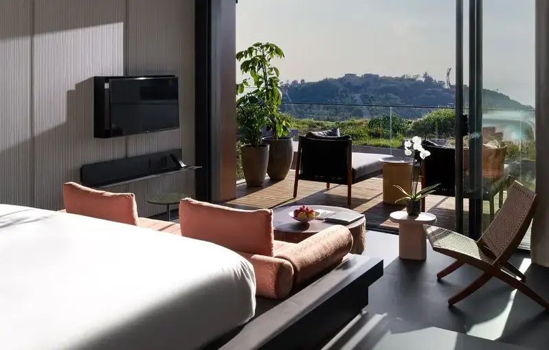 Modernes Hotelzimmer mit Doppelbett, Sitzbereich und Zugang zur Holzterrasse.