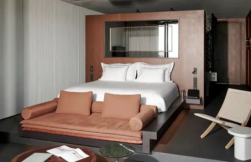 Doppelbett mit weißer Bettwäsche und terracottafarbener Sitzbank.