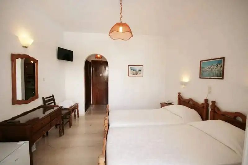 Helles Hotelzimmer mit zwei Einzelbetten aus Holz und Durchgang zum Flur.