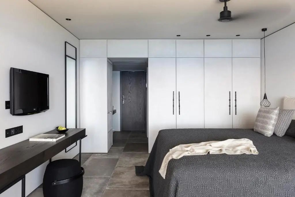 Schlafzimmer mit Doppelbett, Sitzhocker, Spiegel und weissen Schranktüren