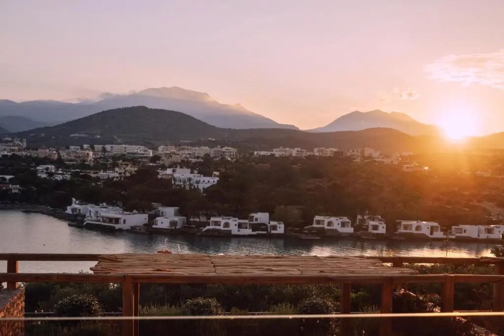Panoramablick auf eine Bucht mit weißen Gebäuden und Bergen im Licht der Abendsonne.