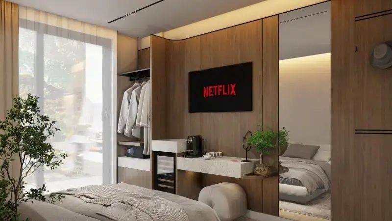 Moderne Holzverkleidung im Hotelzimmer mit Fernseher, Minibar und offenem Kleiderschrank.
